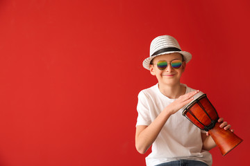 Teenage boy playing drum against color background