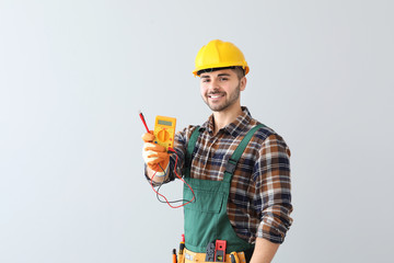 Male electrician on light background