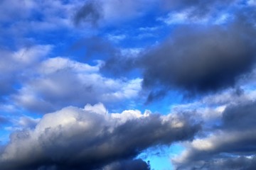Interesting white and dark mixed cloud formations on a blue sky in spring