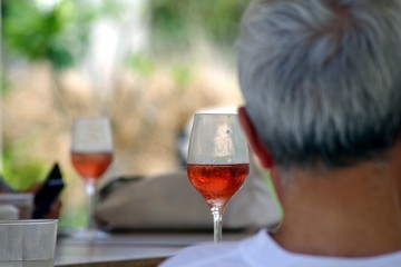 Glasses of rosé wine on a table with a back of a man in the foreground, favorite drink for the...