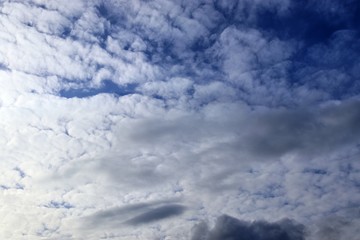 Interesting white and dark mixed cloud formations on a blue sky in spring