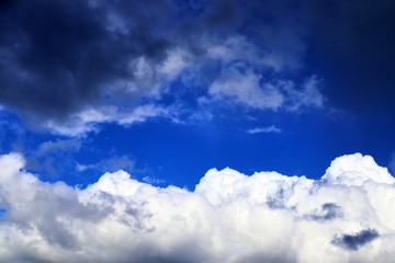 Interesting white and dark mixed cloud formations on a blue sky in spring
