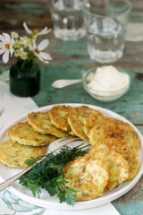 Pancakes with zucchini and sweet corn, served with sour cream, parsley and dill. Vegetarian food.