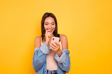 Close up photo beautiful she her lady  telephone hands arms bite mouth teeth index finger reader news funny funky wear casual pastel tank-top jeans denim jacket isolated yellow bright background