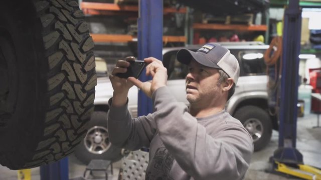 A mechanic records the parts of a vehicle with his phone