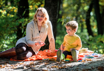 Mom and kid boy relaxing while hiking in forest. Family picnic. Mother pretty woman and little son sit on plaid relaxing forest picnic. Good day for spring picnic in nature. Explore nature together