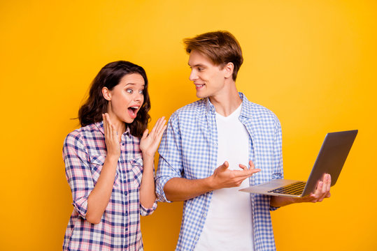 Close up photo of pair teens he him his she her lady boy with computer in hands great news won play pen-friend comes to visit them wearing casual plaid shirts outfit isolated on yellow background