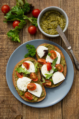 Mozzarella cheese, cherry tomatoes and pesto bruschetta, toast on wooden background. Healthy breakfast ,snack. Pesto pasta.