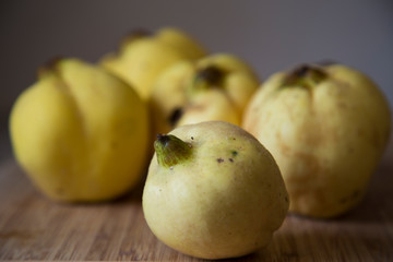 Freshly picked homegrown organic yellow quinces with fuzz getting ready to be washed and made into quince jelly and paste, with wooden chopping board.