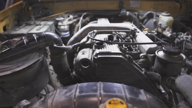 Close up at the hand of a mechanic while removing the oil cap of a car engine
