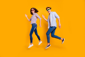 Fototapeta na wymiar Close up full length body size photo of pair in summer specs he him his she her lady boy make dance moves jumping high fooling around wearing casual plaid shirt outfit isolated on yellow background