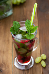 Fresh fruit tea with strawberry in glass cup with straw, summer fruit tea drink, wooden background