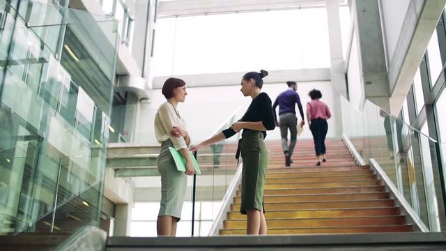 Group of young businesspeople standing and walking on a staircase, talking.