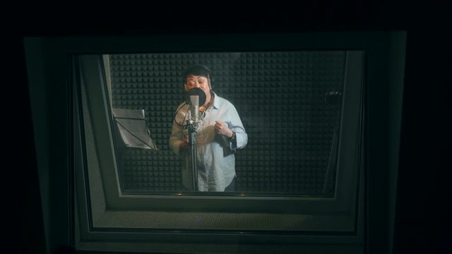 Singing woman in a recording studio. Adult woman recording a song in a recording studio.