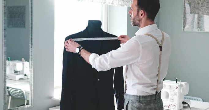 Tailor measuring jacket suit on mannequin at fashion design workshop