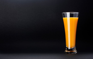 Glass of orange juice isolated on black background with copy space for text, fresh citrus cocktail