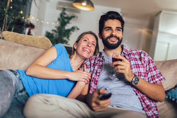 Beautiful young couple watching TV in living room.