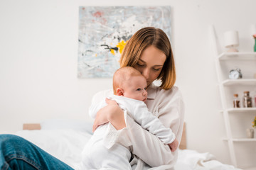 Happy mother in white shirt holding baby at home