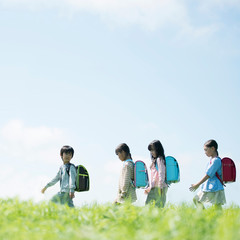 一列で草原を歩く小学生