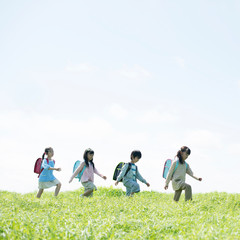一列で草原を歩く小学生