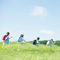 一列で草原を歩く小学生