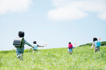 風車を持ち草原を走る小学生