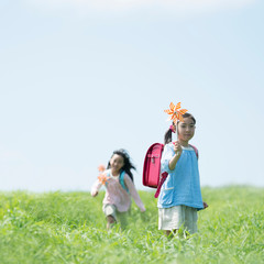 草原で風車を持ち微笑む小学生