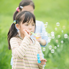 草原でシャボン玉をする小学生