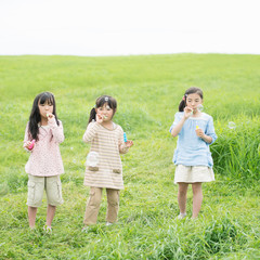草原でシャボン玉をする小学生