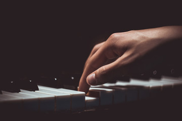 one male hand on the piano. The palm lies on the keys and plays the keyboard instrument in the music school. student learns to play. hands pianist. black dark background