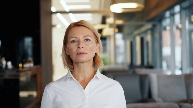 Portrait of confident mature woman businesswoman looking at camera with straight face standing in cafe alone. Confidence, business lunch and senior people concept.