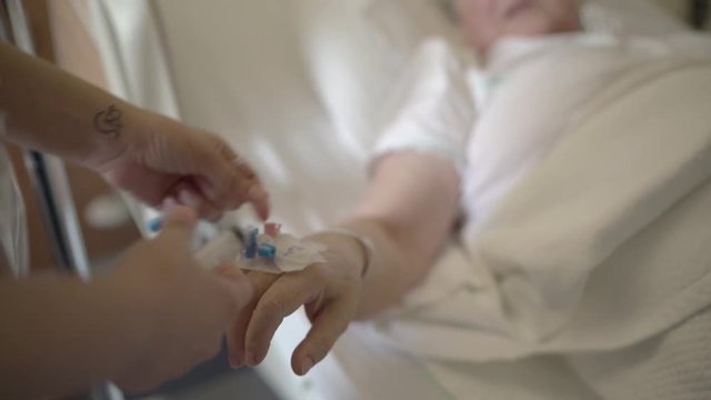 A nurse injecting medicine to an old lady via scalp vein needle