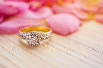 Jewelry diamond ring on wood table with beautiful pink rose petal background close up