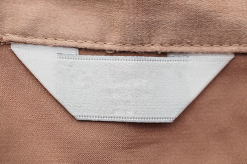 blank white clothing label on brown fabric texture background
