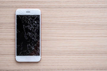 broken glass of mobile phone screen on wooden background