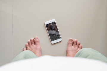 Man looking at mobile phone with broken glass screen on the floor