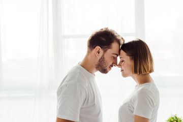 side view of happy loving couple standing with closed eyes at home