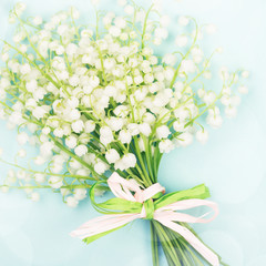 Bouquet of lily of valley on blue background.