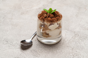 portion of Classic tiramisu dessert in a glass on concrete background
