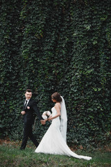 Attractive couple newlyweds is walking back on a trail. Happy and joyful moment. bride and groom hugging in blooming spring garden. beautiful bouquet