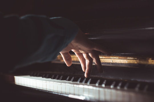 one male hand on the piano. The palm lies on the keys and plays the keyboard instrument in the music school. student learns to play. hands pianist. black dark background