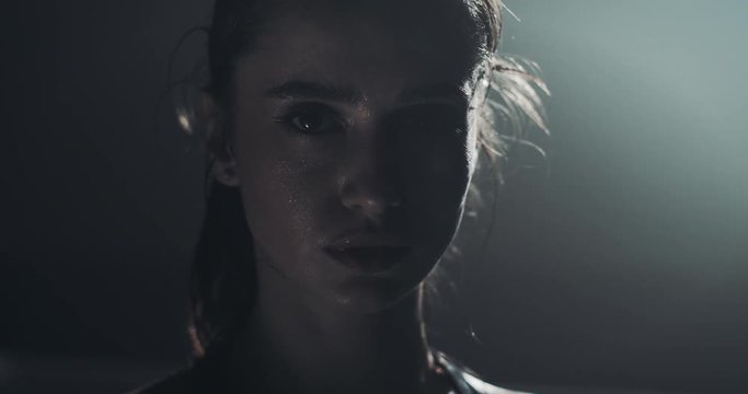 Portrait of tired female boxer standing on the boxing ring and looking at the camera