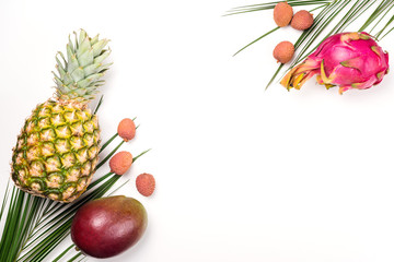 Exotic fruits on a white background, copy space. Pineapple, mango, dragon fruit, lychee. Top view of tropical fruits. Healthy food concept. Fresh fruit flat lay