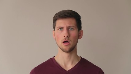 Young man being surprised and acting in negation with strong emotions, medium close-up facing camera still shot