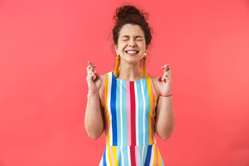 Concentrated pretty redhead woman in dress praying with crossed fingers