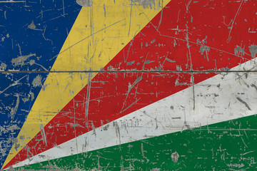 Grunge Seychelles flag on old scratched wooden surface. National vintage background.