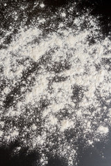 White flour is poured on a black table before cooking cookies