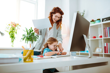 Fototapeta na wymiar Red-haired mom laughing while teaching her girl using keyboard