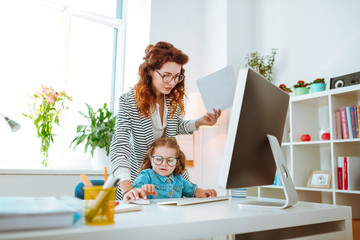 Businesswoman working on computer and playing with daughter