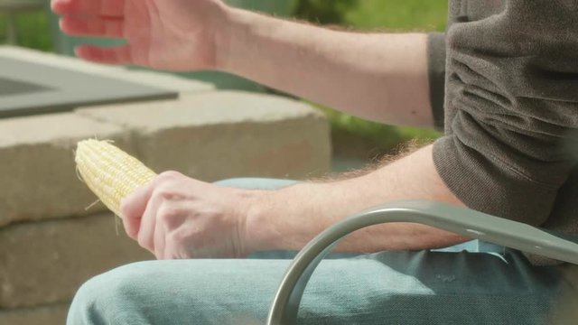 Man Brushing Off Corn on the Cob on Patio TILT UP CLOSE UP SLOW MOTION